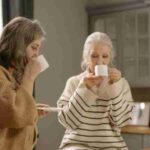 Two senior women relaxing and sipping coffee at a kitchen table, enjoying each other's company., tags: die - pexel