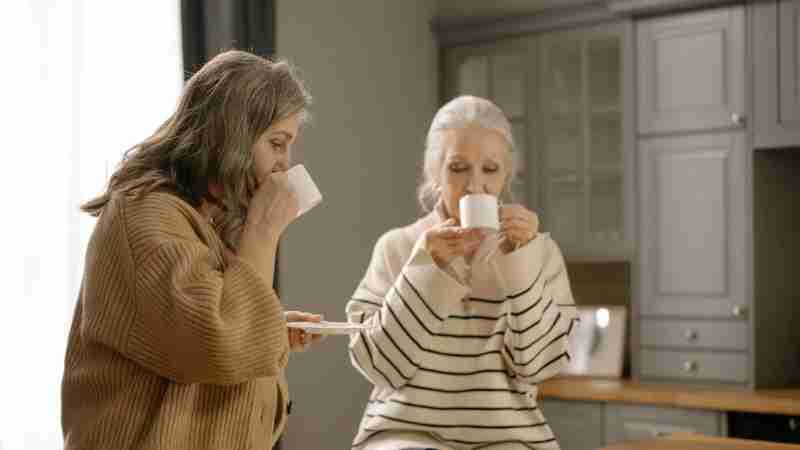 Two senior women relaxing and sipping coffee at a kitchen table, enjoying each other's company., tags: die - pexel