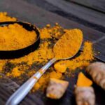 Vibrant turmeric powder and root on a dark wooden surface, emphasizing natural spices., tags: und - pexel